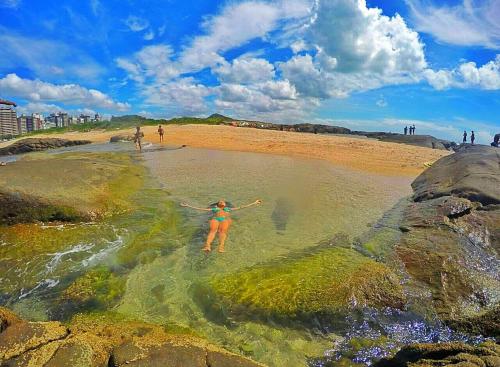 a woman standing in the water at a beach at Vila Suítes Coliving in Vila Velha