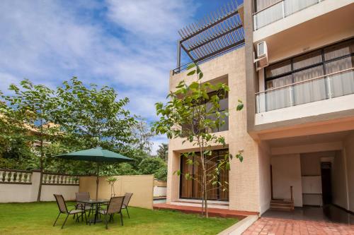 a patio with a table and chairs and an umbrella at StayVista's Greenwoods Villa 1 - City-Center Villa with Private Pool, Terrace, Lift & Carrom Board in Lonavala