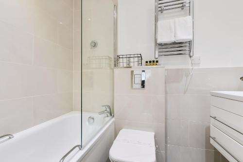 a white bathroom with a toilet and a shower at Nell Gwynn Chelsea Accommodation in London