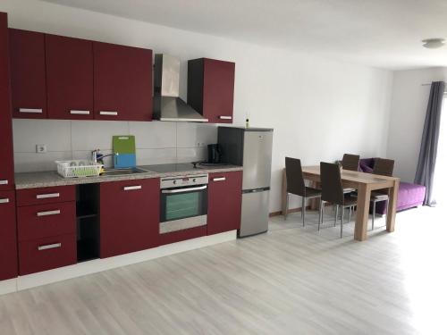 uma cozinha com armários vermelhos e uma mesa com cadeiras em Stundenhotel Krieger em Büren