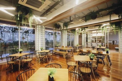 a restaurant with tables and chairs and plants at Laekhon Nonbai in Nakhon Si Thammarat