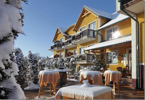 um grupo de cadeiras cobertas de neve em frente a um edifício em Gasthof Großschedl zum Kramerwirt em Lassnitzhöhe