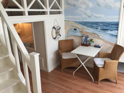 a table and chairs in a room with a painting of the ocean at B&B 'De Bedstee' in Rijnsburg