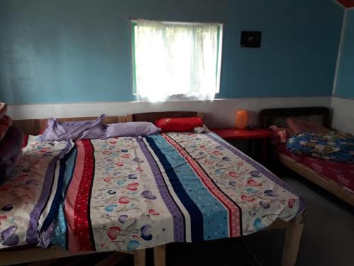 a bedroom with a bed with a colorful quilt on it at Gopal Homestay in Sukhia Pokhari