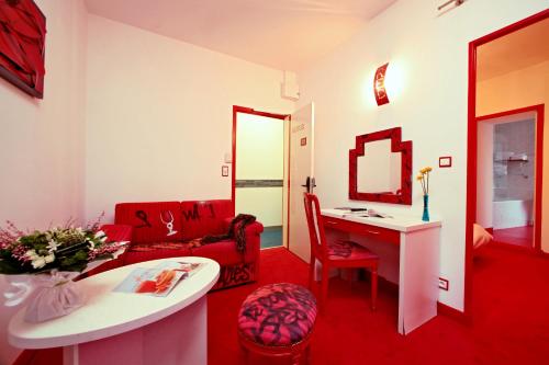 sala de estar con escritorio y sofá rojo en Hôtel Le Coin des Halles, en Cahors