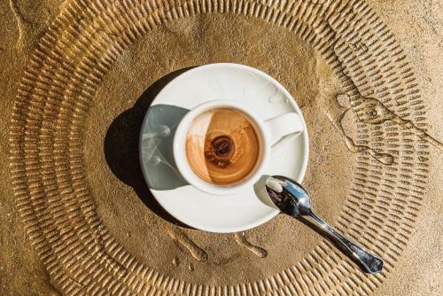 a cup of coffee on a plate with a spoon at Emma's kleines Hotel in Ramsau im Zillertal