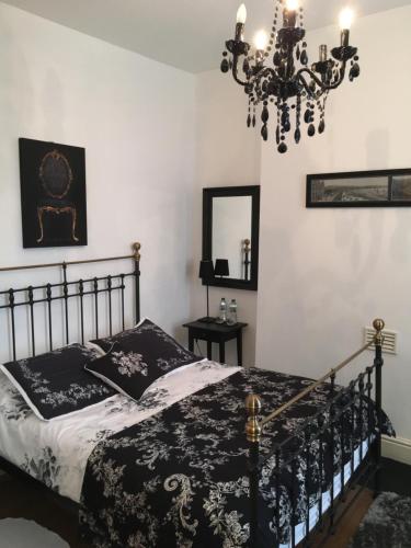 a bedroom with a black and white bed and a chandelier at Raymonds in Douglas