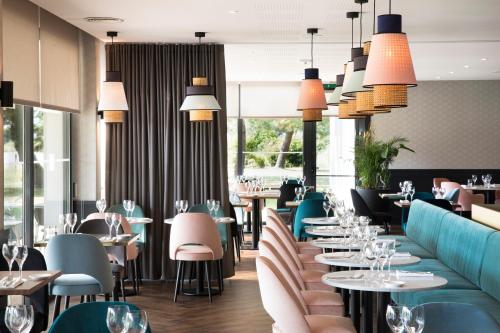 a restaurant with tables and chairs and lights at Best Western Plus Hotel les Rives du Ter in Larmor-Plage