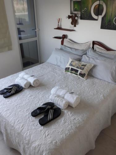 Una cama con toallas y chanclas. en Complejo Sol&Luna en Villa Ventana