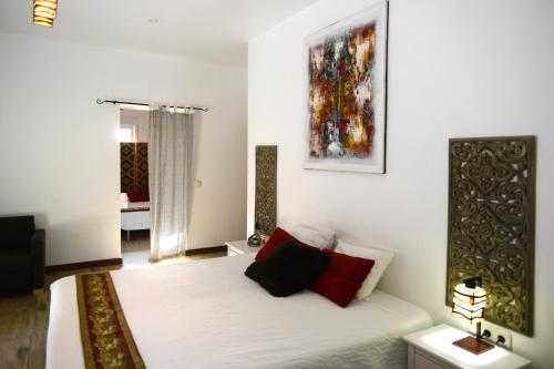 a white room with a bed with red pillows on it at Cortijo Oro Verde B&B in Tabernas