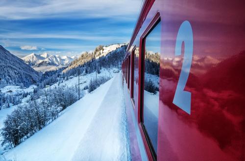 a red train traveling through a snow covered mountain at Schloss Hotel & Spa Pontresina in Pontresina