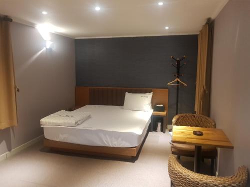 釜山的住宿－陽光汽車旅館，卧室配有1张床、1张桌子和1把椅子