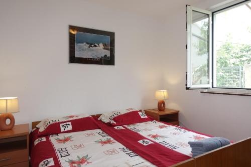 um quarto com uma cama com um edredão vermelho e branco em Dragica Apartments em Vrsi