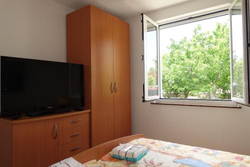 um quarto com uma televisão de ecrã plano e uma cama em Dragica Apartments em Vrsi