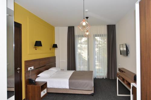 a bedroom with a bed and a yellow wall at Hotel Garnet Tbilisi in Tbilisi City