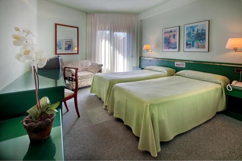 una habitación de hotel con 2 camas y una silla en Hotel Rey Sancho Ramírez, en Barbastro