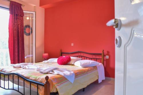 een slaapkamer met rode muren en een bed met kussens bij Vicky's Village private House in Fiolítis