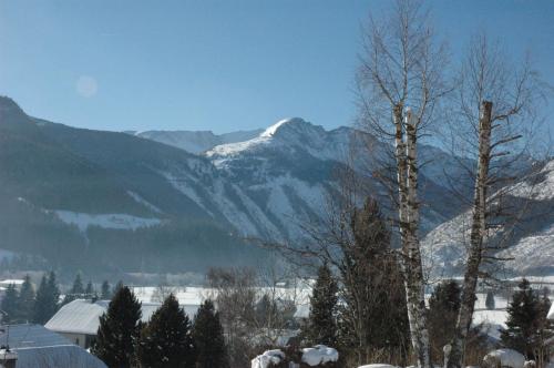 a snow covered mountain range with a town and a tree at Appartement Haus Moser in Sankt Michael im Lungau