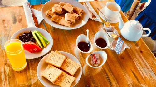 a wooden table with plates of breakfast foods and drinks at Tyre Boutique Apartments in Soûr