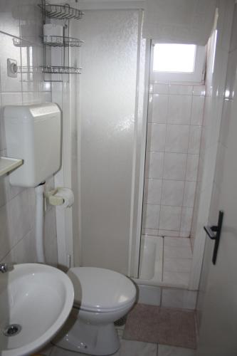 a white bathroom with a toilet and a shower at Sobe Stipe in Primošten