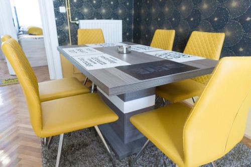 a dining table with yellow chairs in a room at Luxory Apartment The Soul Of City in Maribor