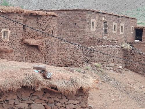 an old brick building with a straw roof at Maison d'Hôtes Agdal Telouet in Tiguidert