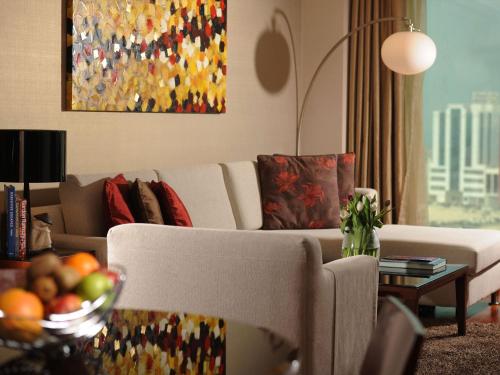 a living room with a couch and a table with a bowl of fruit at Fraser Suites Seef Bahrain in Manama