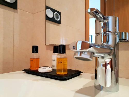 - un comptoir de cuisine avec 2 bouteilles de savon et un robinet dans l'établissement Residencial Playa Poniente, à Gijón