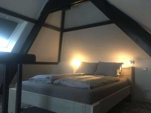 a bed in an attic with a light on it at Pakhuis 5 in Katwijk aan Zee