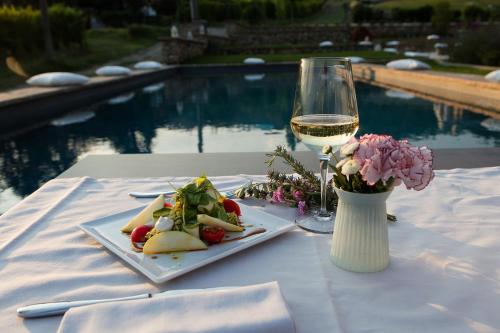 a table with a plate of food and a glass of wine at Agriturismo La Ratta in Vernasca