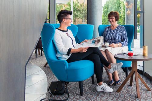 a man and a woman sitting in a blue chair at Mercure Blankenberge in Blankenberge
