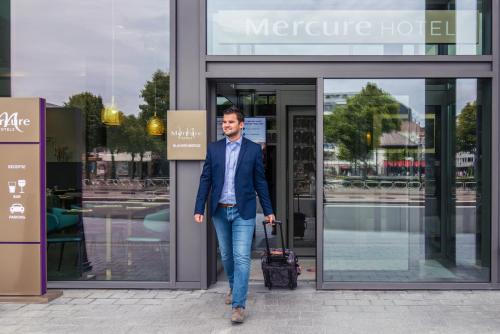 a man in a suit walking out of a store at Mercure Blankenberge in Blankenberge