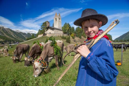 a young boy wearing a hat and holding a rope with cows at Schloss Hotel & Spa Pontresina in Pontresina
