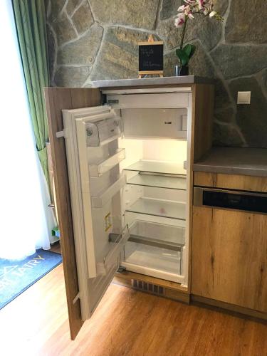 an empty refrigerator with its door open in a kitchen at ORBIT TATRY Apartments, Starý Smokovec, Vysoké Tatry in Smokovce