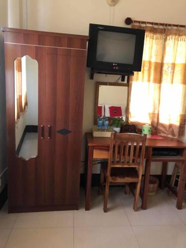 pokój z biurkiem, telewizorem i drewnianą szafką w obiekcie A Tee Guesthouse w mieście Luang Prabang