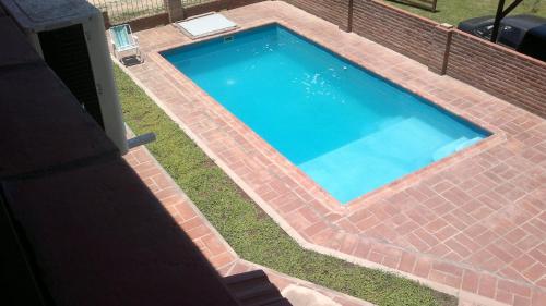 a brick swimming pool with a blue poolvisor at Las Acacias in Nono