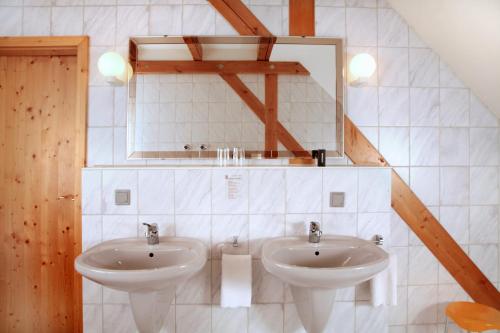 a bathroom with two sinks and a mirror at Hotel Rodebachmühle in Georgenthal
