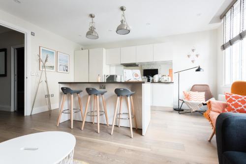 cocina y sala de estar con encimera y taburetes en The Oxford Street Studio - 1BDR in Paddington, en Londres