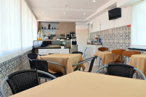 a restaurant with tables and chairs and a kitchen at Hotel Visconde in Porto