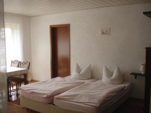 Schlafzimmer mit einem Bett mit weißer Bettwäsche und Kissen in der Unterkunft Harzer Ferienpension in Timmenrode