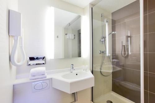 a white bathroom with a sink and a shower at Kyriad Hotel Nevers Centre in Nevers