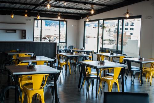 un restaurante vacío con mesas y sillas amarillas en Hotel Plaza Carnaval, en Pasto