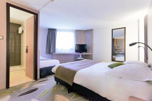 a hotel room with a large bed and a mirror at Kyriad Hotel Nevers Centre in Nevers