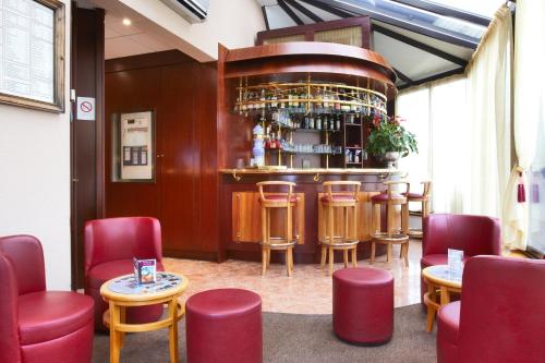 a bar in a restaurant with red chairs and tables at Kyriad Hotel Nevers Centre in Nevers