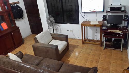 sala de estar con sofá, escritorio y pantalla en Casa Puerto Ayora, en Puerto Ayora