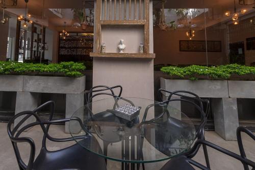 a glass table and chairs in a room with plants at Pearl Royal Hotel, Colombo in Colombo