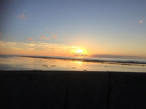 a sunset on a beach with the sun setting at Shoreline Escape Rarotonga in Rarotonga