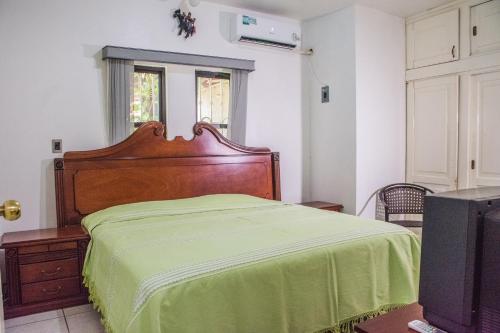 a bedroom with a bed with a green blanket at Casa grande y privada, jardín & estacionamiento in Salina Cruz