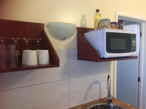 a kitchen with a microwave on a shelf above a sink at Shoreline Escape Rarotonga in Rarotonga