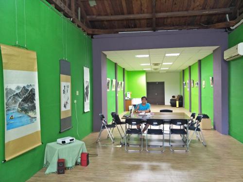 a woman sitting at a table in a room with green walls at 博愛泊旅讀心境 in Hualien City